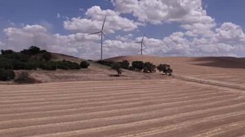 A drone over farmers' fields on a cloudy day. Wind turbines are operating in the fields. video