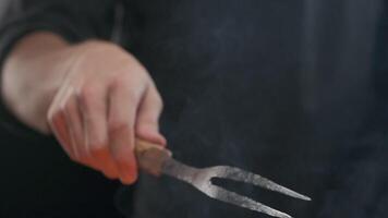 Hand of a chef with a large fork in a steaming grill video