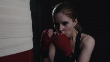 Female fighter tired in sweat practicing hard punches on a punching bag video