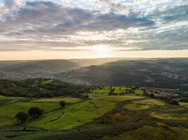 Sun shining over green valley with towns in wales photo