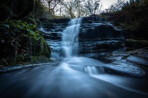 Waterfall cascading down mossy rocks in tranquil forest setting photo