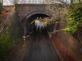 Narrow road passing under a brick bridge in autumn photo