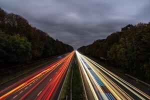 Highway traffic at dusk showing vehicle light trails creating speeding effect with cloudy sky background photo