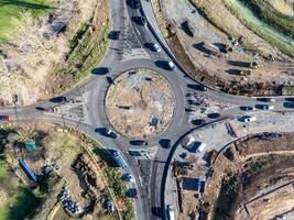 Cars driving on roundabout under construction, aerial view of road work photo