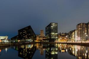 The modern buildings of liverpool are reflecting in the water of the docks photo