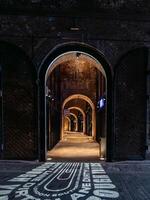 Empty illuminated brick archway walkway leading to shops photo
