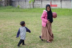 Joyful Muslim Mother and Son Playing with a Ball Outdoors photo