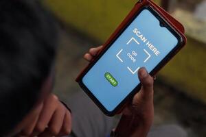 Man Holding Smartphone Scanning QR Code with Mobile App photo