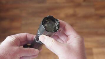 A metallic flashlight held in hands, with a power button on the body video
