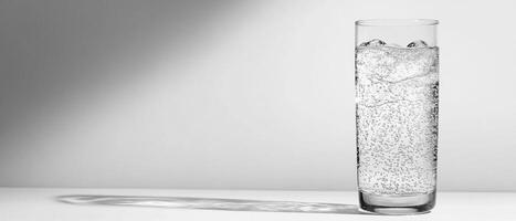 Minimalist glass of sparkling water with ice on a clean white background, with copy space photo