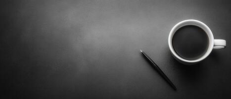 Top View of a White Coffee Cup and Black Pen on a Dark Textured Desk with Copy Space photo