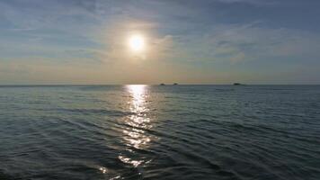 Ripples gently crashing to the shore in the evening under sunlight with cloudy blue sky. Tranquil scene of the sea before sunset. video