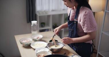 Mano alto ángulo ver disparo, hermosa mujer es preparando el proceso de revestimiento pollo con todas el ingredientes en un cuenco antes de fritura el pollo en un cacerola. Cocinando concepto, comida preparación video