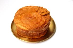 Croissant roll or timbering on yellow metal round dish on white background. photo