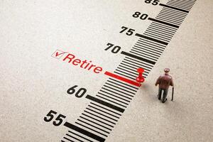 Red pin on retire scale with little senior man doll on paper background. Concept of retirement planning finance, health insurance and living a happy and secure retirement life. photo