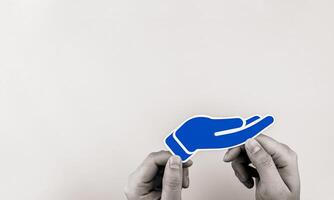 A paper hand on a white background with copy space. Concept of donation for foundations and charities, financial assistance, or health donations. photo