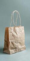 Crumpled brown paper shopping bag with handles on light background photo