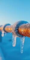 Icy Pipeline in Winter Landscape with Frozen Icicles and Clear Blue Sky at Sunrise photo