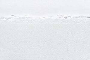Close-up of textured torn white paper edge with detailed fibers and rough surface. photo