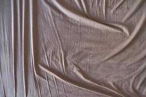 Natural beige fabric with wrinkles and texture highlighting soft cotton material surface. photo