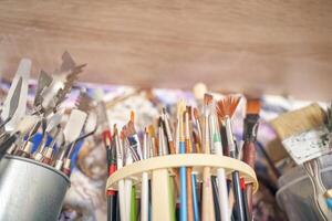 Assorted paint brushes and art tools in studio setting for creative painting projects. photo