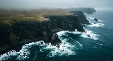 Aerial View of a Majestic Ocean Cliffs Engulfed in Fog with Waves Breaking Against Rocks photo