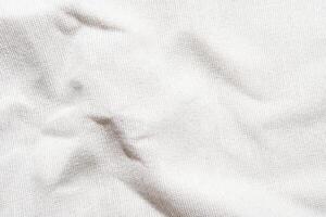 Close-up texture of white wrinkled canvas fabric with subtle shadows. photo