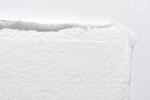 Close-up of textured white paper edge with subtle shadow on light background. photo