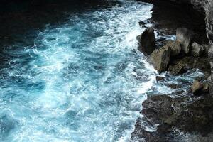 Landscape aerial view of surf and aqua surface in the sea with foam waves and splash water of ocean with rocky cliff beach photo