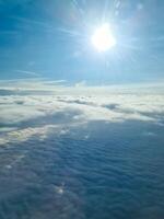 The sun shining over a sea of clouds from airplane window photo