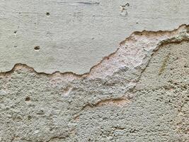 Old damaged plaster wall with holes and cracks showing underlying layer photo