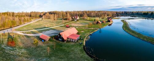 Riga, Latvia, 2024 - Rural Settlement with Red Roofed Buildings by a Winding Waterway photo