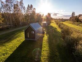 Riga, Latvia, 2024 - Modern Cabin with Metal Roof in Rural Landscape at Sunset photo