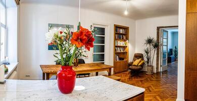 Riga, Latvia, 2024 - Modern Kitchen and Dining Area with Vibrant Red Vase and Flowers photo