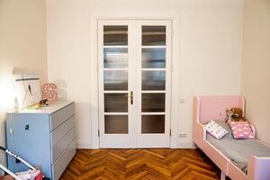 Riga, Latvia, 2024 - Childrens Room with Pink Bed and Herringbone Wooden Floor photo