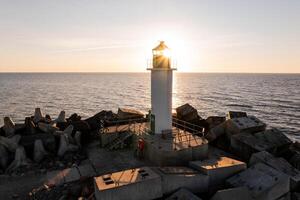 Riga, Latvia, 2024 - Lighthouse Silhouette on Breakwater at Sunset with Ocean Horizon photo