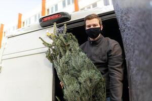 Person Unloading Christmas Tree from Van in Urban Setting photo