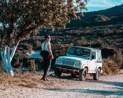 Man Standing by White Off Road Vehicle on Dirt Path in Rugged Terrain photo