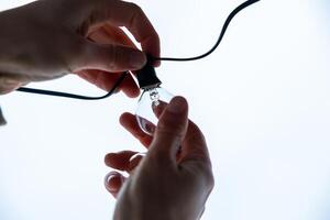 Hands Installing an LED Bulb into a Black Socket on a Wire photo