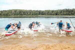 Group Launching Paddleboards into a Calm Lake with Forest Backdrop photo