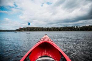 Red Kayak on Calm Lake with Forested Shoreline and Floating Platforms photo