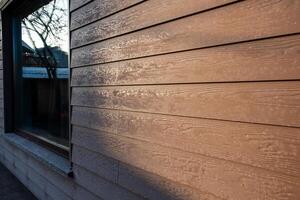 Exterior Wall with Wooden Paneling and Reflected Tree in Window photo