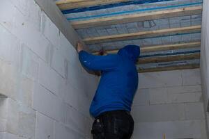 Person Working in Unfinished Room with Exposed Wooden Beams photo