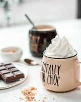 Close Up of Mug with Whipped Cream and Chocolate Bar Nearby photo