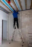 Worker on Ladder Installing Ceiling with Exposed Wooden Beams photo