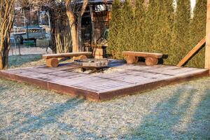 Wooden Deck with Fire Pit and Benches Amid Frosted Evergreen Trees photo