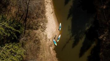 Aerial View of Riverbank with Paddleboards and Sparse Trees photo