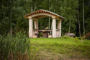 Rustic Wooden Gazebo with Table and Benches in Forest Setting photo
