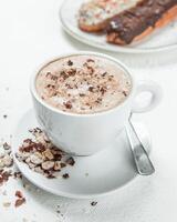 Coffee Cup with Frothy Beverage and Eclairs on White Surface photo