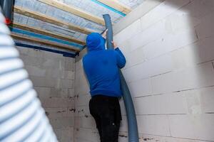 Person Installing Ventilation Duct in Room with Exposed Wooden Beams photo
